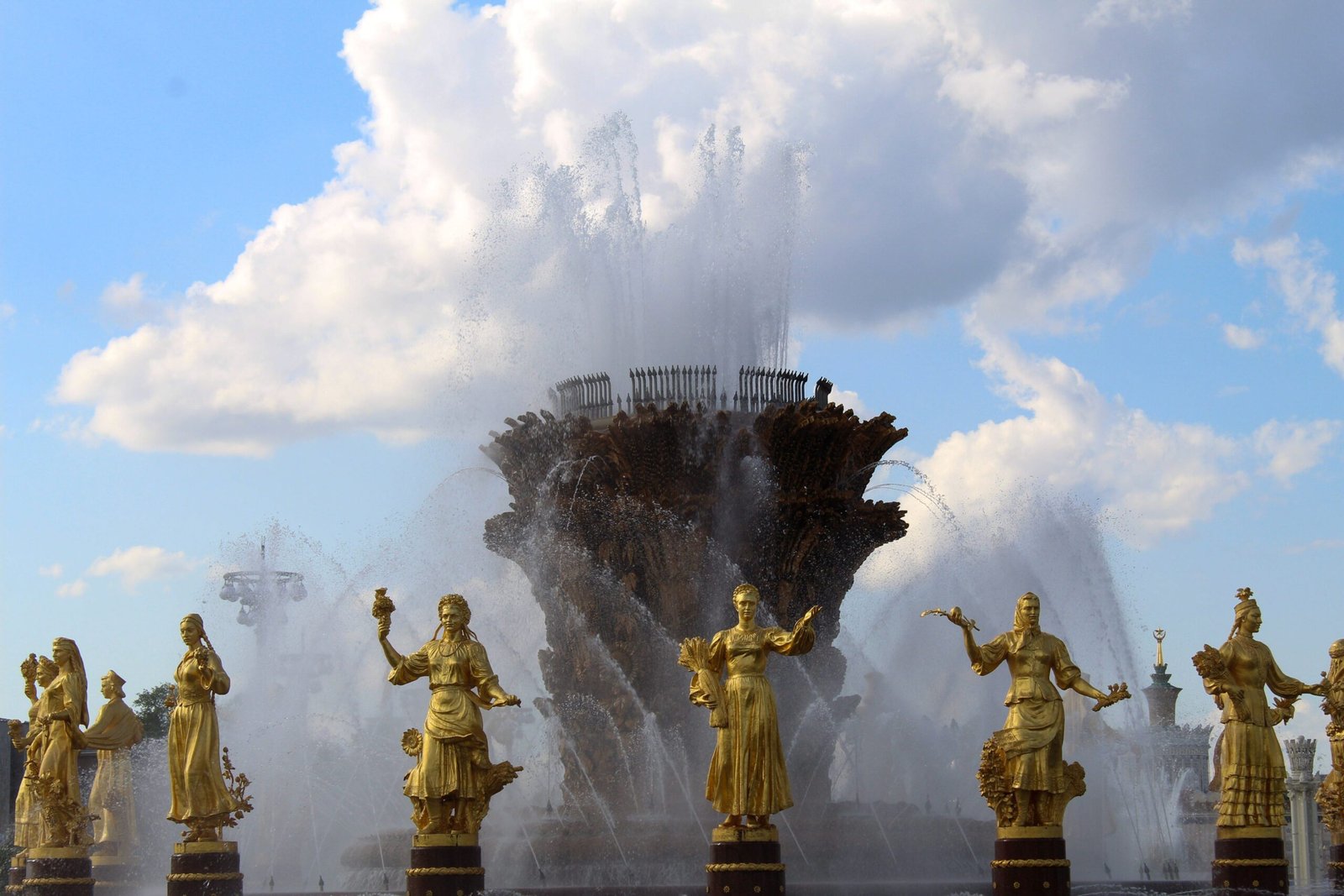 Stunning fountain with golden statues under a blue sky at VDNKh, showcasing artistic craftsmanship.