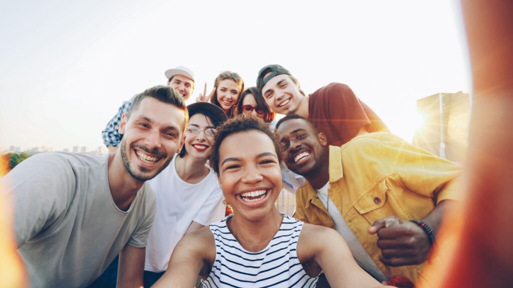 Education One-Liner Questions A diverse group of friends taking a joyful selfie outdoors during sunset.